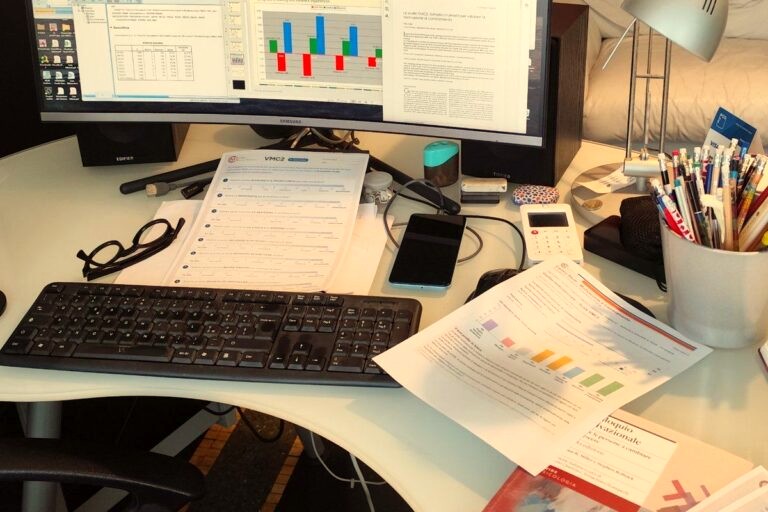 Scrivania con computer, grafici e materiali di ricerca